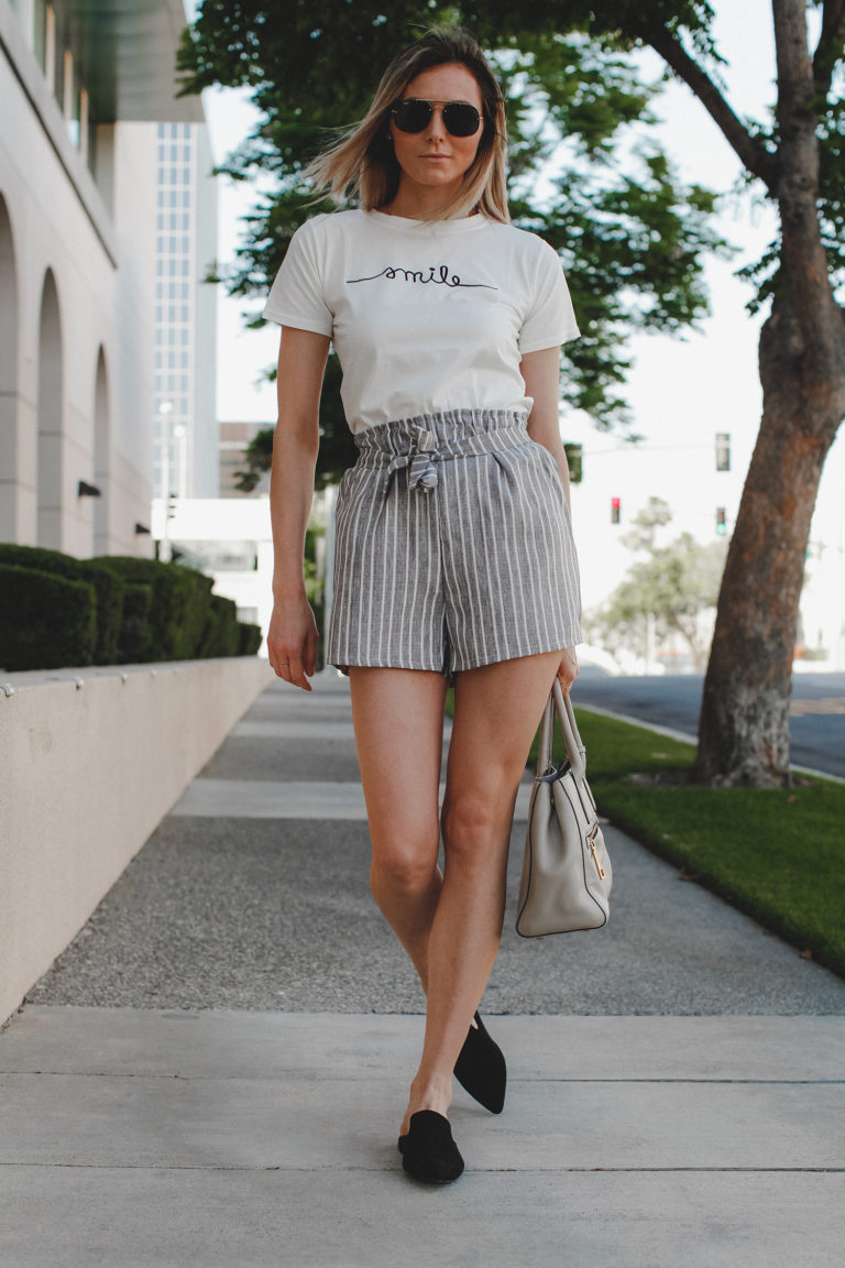 Paper bag shorts trend featured by top US fashion blog, Tea Cups & Tulips: image of a woman wearing Light grey paper bag shorts and a smile tee