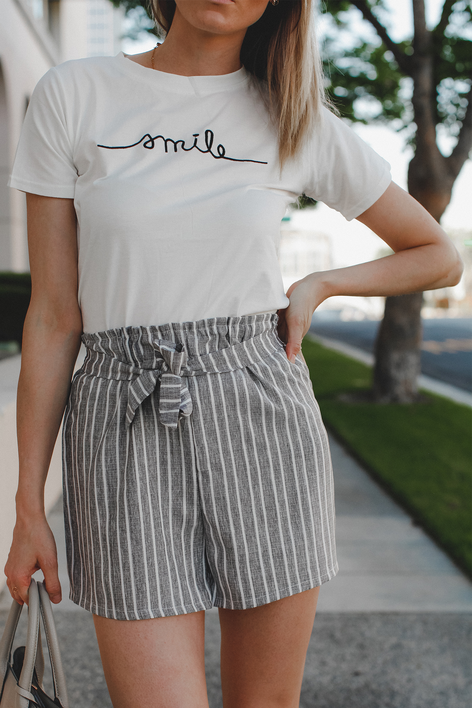 Paper bag shorts trend featured by top US fashion blog, Tea Cups & Tulips: image of a woman wearing Light grey paper bag shorts and a smile tee