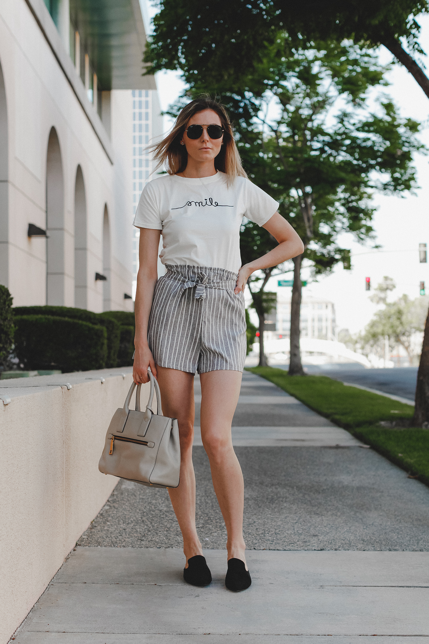 Paper bag shorts trend featured by top US fashion blog, Tea Cups & Tulips: image of a woman wearing Light grey paper bag shorts and a smile tee