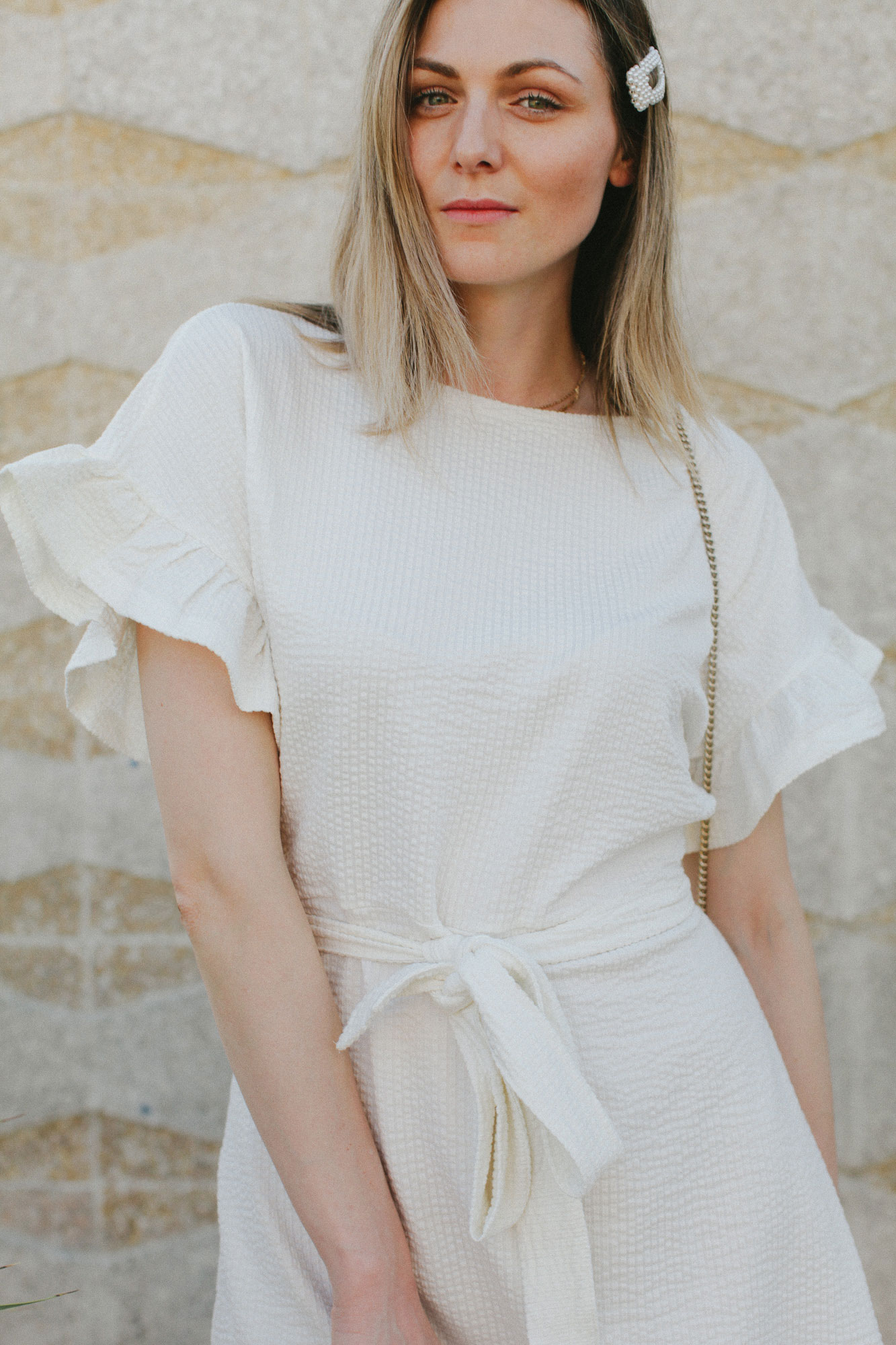 Cute summer ruffle dress styled by top US fashion blog, Tea Cups & Tulips: image of a woman wearing an H&M cream ruffle dress, Furla crossbody bag, H&M mules, ASOS hat and Amazon pearl hair clip.