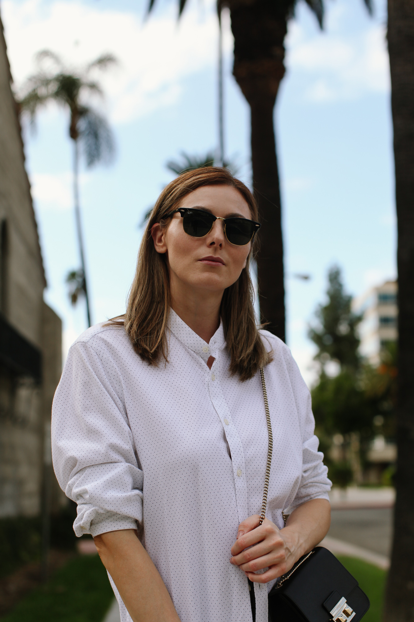 casual wear: white button down shirt | How to Style An Oversized Button Down Shirt by popular Southern California fashion blog, Tea Cups and Tulips: image of a woman outside wearing a Zara oversized button down shirt, Banana Republic Petite Modern Sloan Skinny-Fit Washable Pant with Piping, Ray-Ban sunglasses, Happiness Boutique Circle Pendant Necklace Rose Gold, and FURLA Bella Saffiano Mini Crossbody.